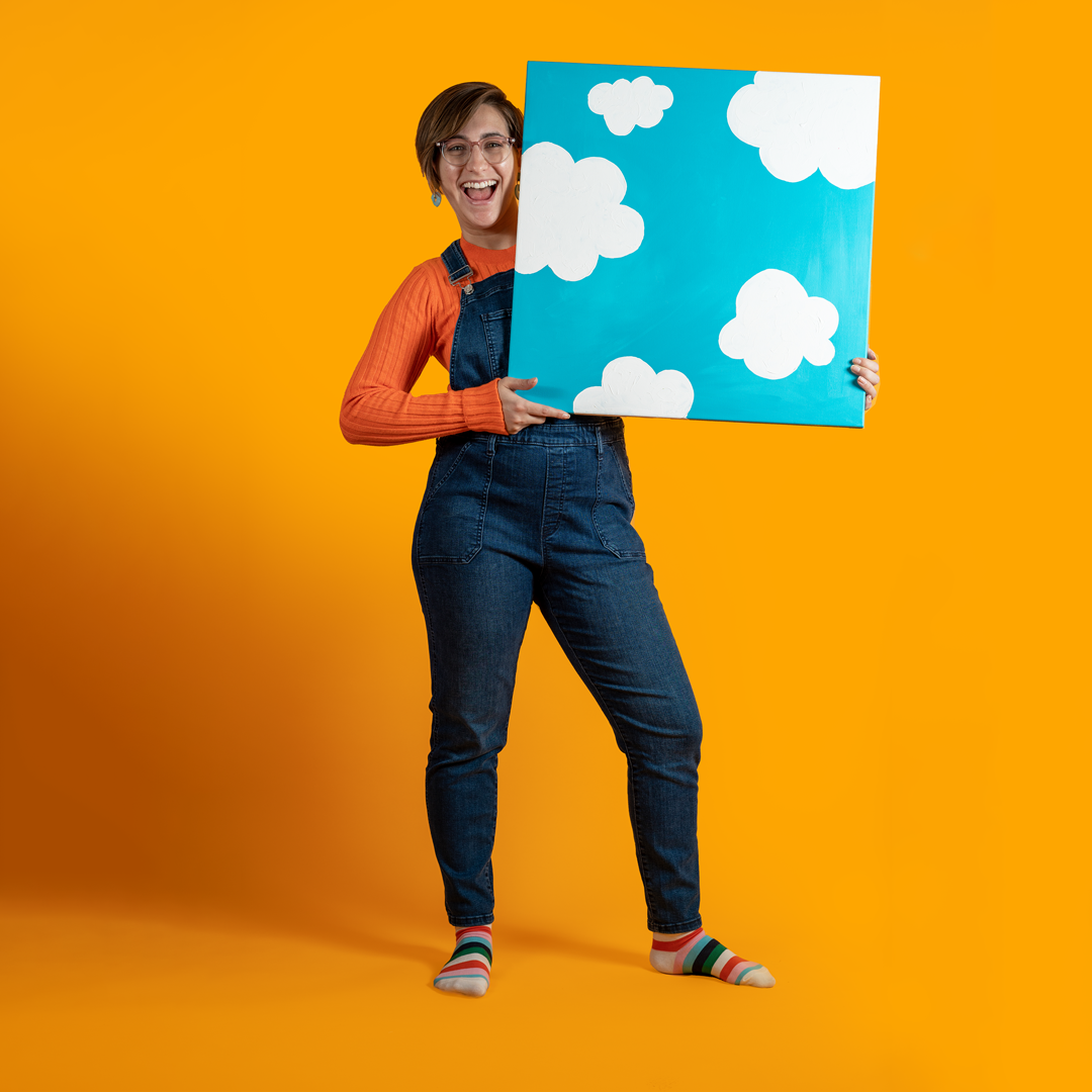 Cat Schmitz holding a 24 inch square painting of white clouds on a blue background.