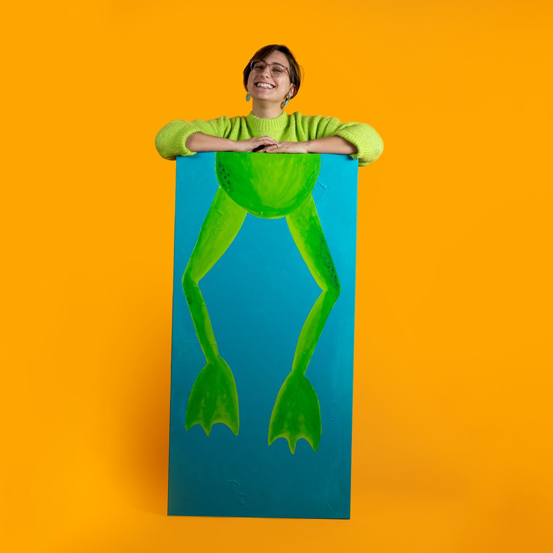 Cat Schmitz standing behind a four foot painting of frog legs.