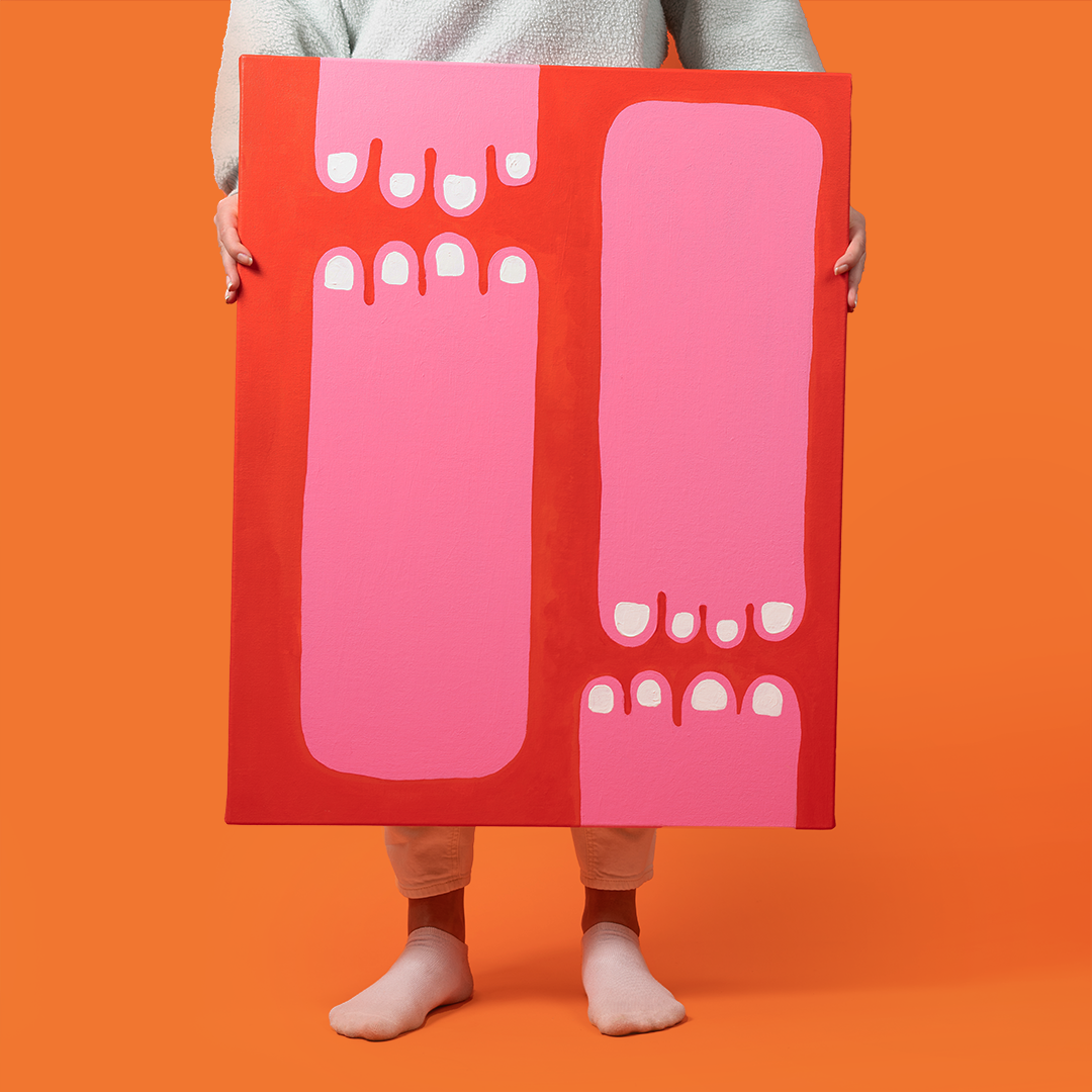 Painting of pink feet on a red background. There is a person holding the painting on an orange background.