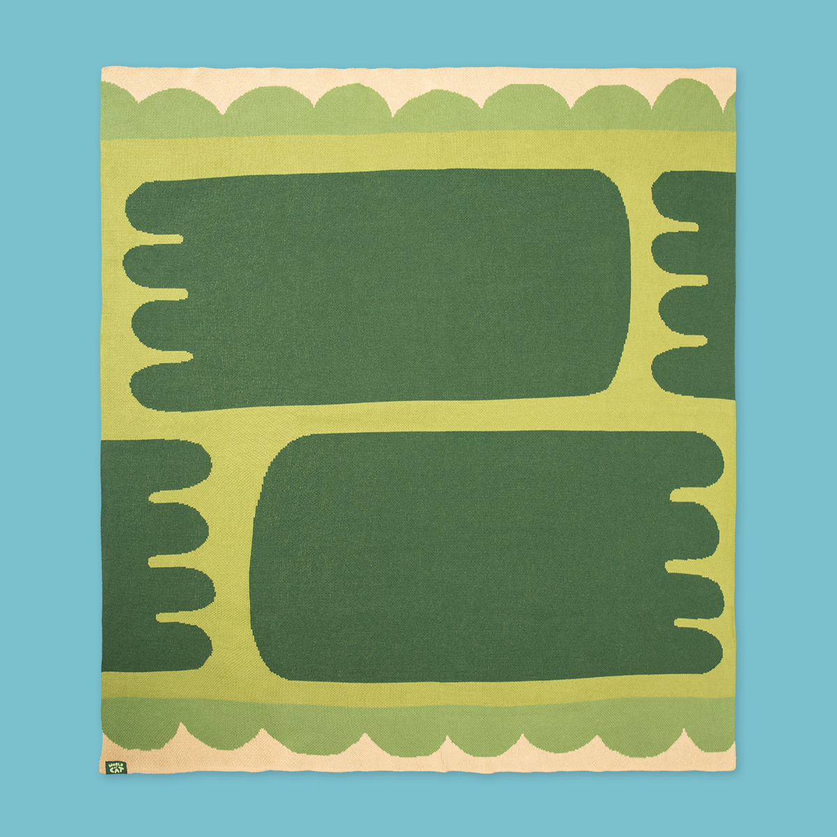 Top down view of blanket. The design has four dark green feet-shaped objects on a light green band with ruffles. The bottom and top edges of the blanket are beige.