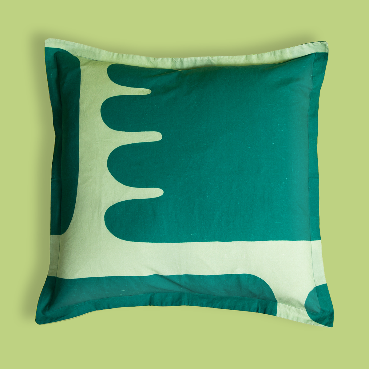 Photo of the front of a pillowcase with dark green toes spilling out onto a light green background.