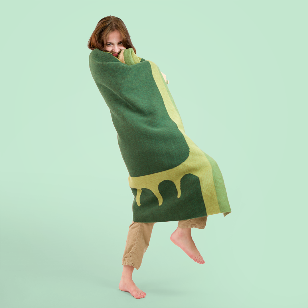 Woman curled up in a green blanket.